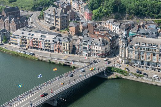 Dinant, Belgium - June 26, 2019: Seen from Citadelle. Charles de Gaulle bridge and intersection with Avenue des Combattants. River Meuse, buildings and cars with green foliage in back.