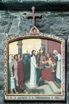 Dinant, Belgium - June 26, 2019: Inside Collégiale Notre Dame de Dinant Church. Closeup of first station of the cross painting featuring judgment and condemnation of Jesus.