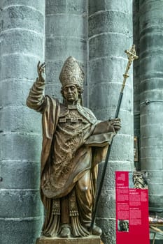 Dinant, Belgium - June 26, 2019: Inside Collégiale Notre Dame de Dinant Church. Gray stone statue of Belgian medieval Saint Lambert against pillar. Red sign with history.