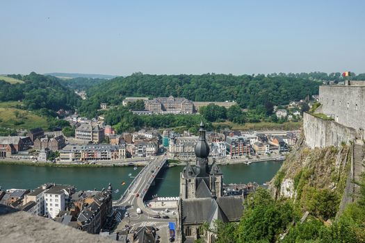 Dinant, Belgium - June 26, 2019: Seen from Citadelle. Large building on top is College Notre Dame de Bellevue, school system from primary to high school. Forests in back. Church and ramparts of Citadelle.