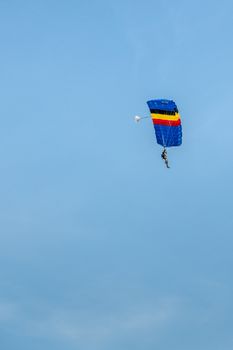 Han-sur-Lesse, Belgium - June 25, 2019: Belgian soldier on parachute with Belgian flag colors against blue sky.