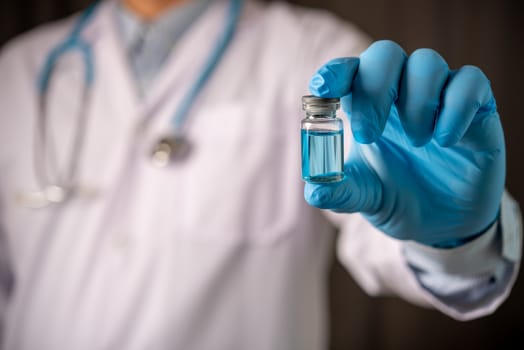 doctor hand holding blue vaccine bottle
