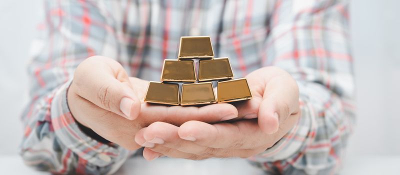 worker man hand holding gold bar stack.