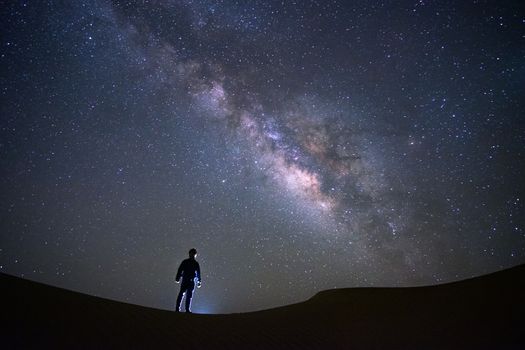 Milky way galaxy with a man standing and watching at Tar desert, Jaisalmer, India. Astro photography.