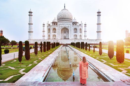 A woman standing front of Taj Mahal when sun rise, an ivory-white marble mausoleum on the south bank of the Yamuna river in Agra, Uttar Pradesh, India. 