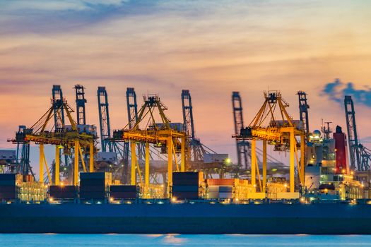 Freighter ship loading cargo at loading dock on twilight time. Singapore, south east asia.