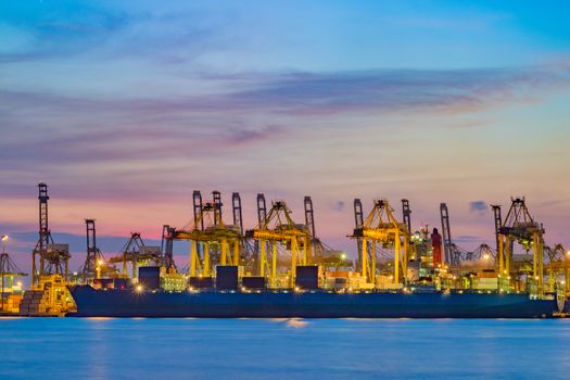 Freighter ship loading cargo at loading dock on twilight time. Singapore, south east asia.