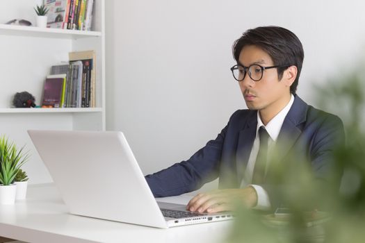 Asian Financial Advisor or Asian Consulting Businessman Seriously Working in front of Laptop. Asian financial advisor or Asian consulting businessman working in office