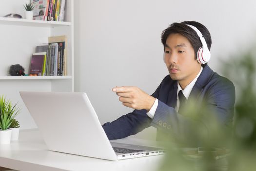 Asian Man Call Center in Suit Wear Headset Seriously Answer Customer Questions. Asian man call center working in front of laptop