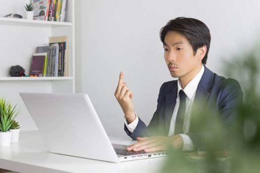 Asian Businessman Angry Partner and Show Middle Finger in front of Laptop. Vulgarity of Asian businessman in pressure condition