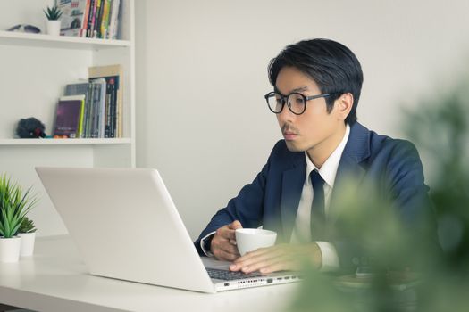 Asian Businessman Wear Eyeglasses Seriously Analyze Financial Data in Laptop. Asian businessman working in office