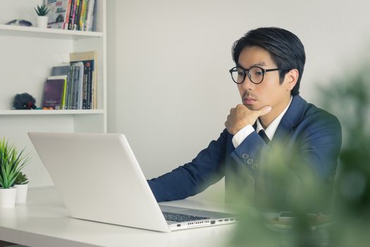Asian Financial Advisor or Asian Consulting Businessman Analyze Financial Information in front of Laptop. Asian financial advisor or Asian consulting businessman working in office