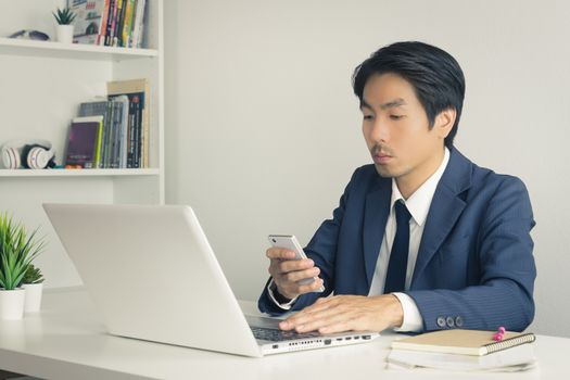 Asian Financial Advisor or Asian Consulting Businessman Sending Message or Chat with Customer. Asian Financial Advisor or Asian Consulting Businessman use smartphone in office