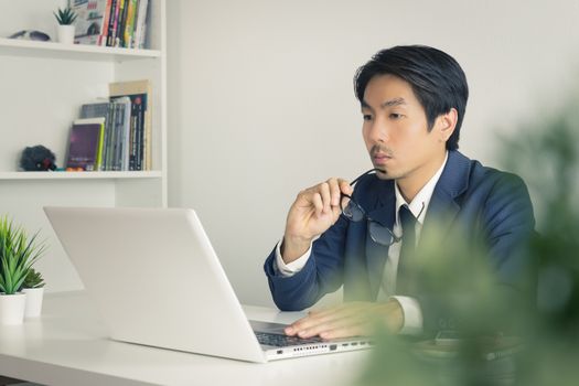 Asian Financial Advisor or Asian Consulting Businessman Serious with Financial Information in front of Laptop. Asian financial advisor or Asian consulting businessman working in office