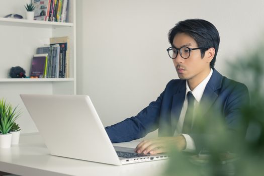 Asian Financial Advisor or Asian Consulting Businessman Seriously Working in front of Laptop. Asian financial advisor or Asian consulting businessman working in office