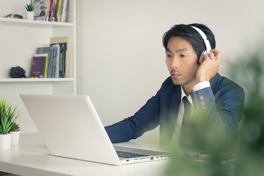 Asian Man Call Center Communicate with Customer via Internet by Laptop with Tree Foreground. Asian man call center answers the customer question in office