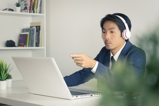 Asian Man Call Center in Suit Wear Headset Seriously Answer Customer Questions. Asian man call center working in front of laptop