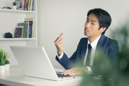 Angry Asian Businessman in Suit Show Middle Finger in front of Laptop Monitor. Agitate Asian businessman with stain with pressure condition in office