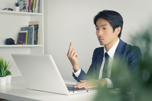 Asian Businessman Angry Partner and Show Middle Finger in front of Laptop. Vulgarity of Asian businessman in pressure condition