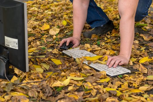 Autumn, a man working at a computer on a fallen yellow foliage in the city on the street