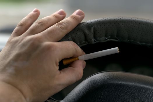 close-up, the hand of the driver of the car with skin disease "vitiligo" holds a cigarette