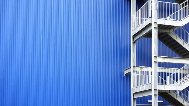 White metal Fire Escape stairs  blue metal wall building background and copy space