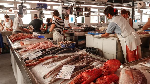 Menorca, Spain - june 28 - 2012 - View of the fish market in Ciutadella de Menorca, with various colorful fish for sale, price tags in the foreground and tourist customers