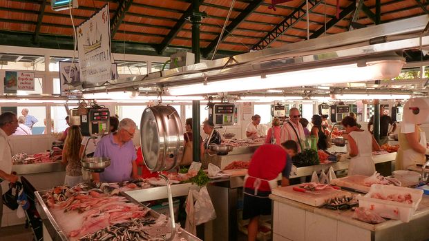 Menorca, Spain - june 28 - 2012 - View of the fish market in Ciutadella de Menorca, with various colorful fish for sale in the  foreground and tourist customers