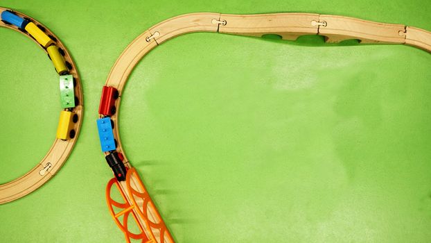TOP VIEW: Wooden toy train on curve wooden railways with green background. Copy space for text 