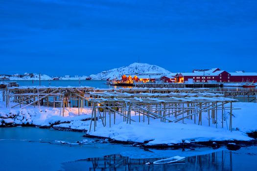Drying flakes for stockfish cod fish in Reine village illuminated at night in winter. Lofoten islands, Norway