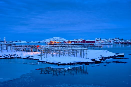 Drying flakes for stockfish cod fish in Reine village illuminated at night in winter. Lofoten islands, Norway