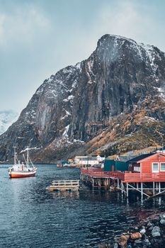 Hamnoy fishing village with ships fishing boats on Lofoten Islands, Norway with red rorbu houses. With falling snow