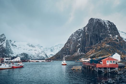 Hamnoy fishing village with ships fishing boats on Lofoten Islands, Norway with red rorbu houses. With falling snow