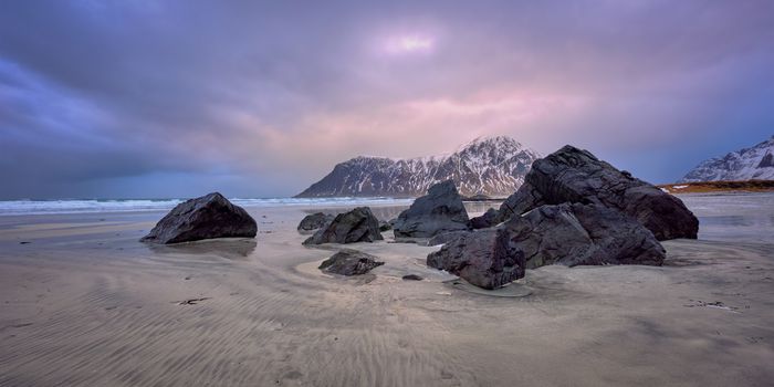 Beach of Norwegian sea on rocky coast in fjord on sunset. Skagsanden beach, Lofoten islands, Norway