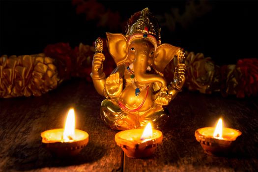 Ganesh Chaturthi or Diwali concept - Ganesha figurine with Diwali lights oil ghee candles, India