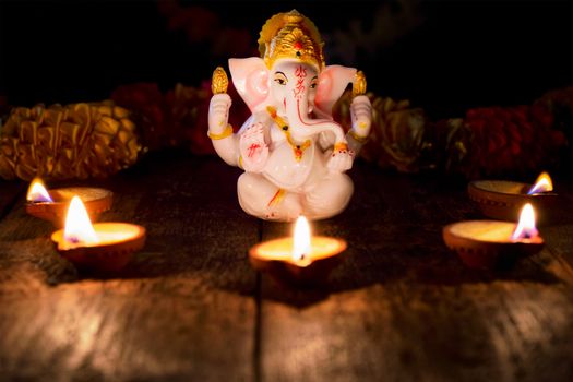 Ganesh Chaturthi or Diwali concept - Ganesha figurine with Diwali lights oil ghee candles, India