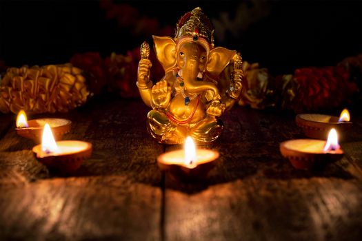Ganesh Chaturthi or Diwali concept - Ganesha figurine with Diwali lights oil ghee candles, India