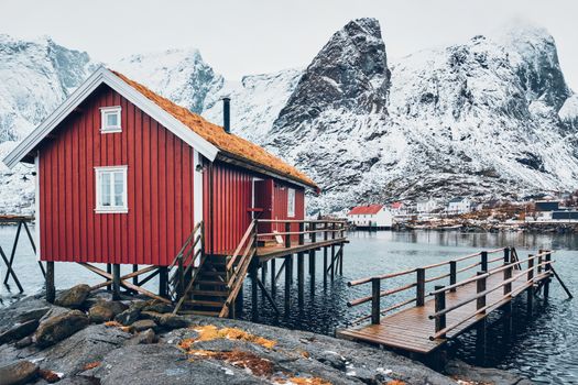 Traditional red rorbu house with grass covered roof in Reine village on Lofoten Islands, Norway in winter