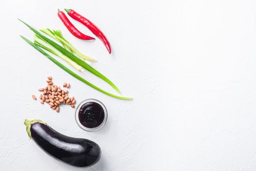 Baked aubergine ingredients, for cooking or grill chili pepper, eggplant, sauce, nuts on white background top view space for text.