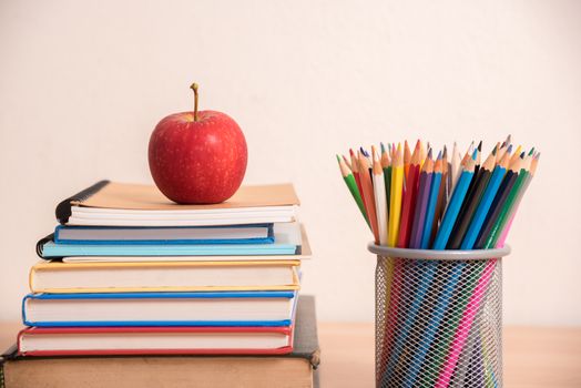 red apple on stack of book with pencil box.