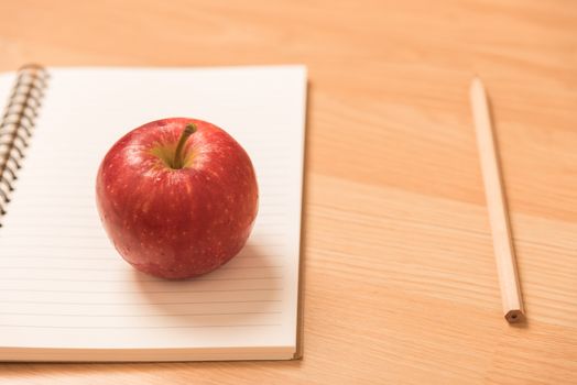 red apple on notebook with a pencil.