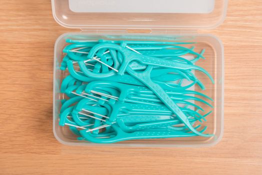 green dental floss picks in plastic box.