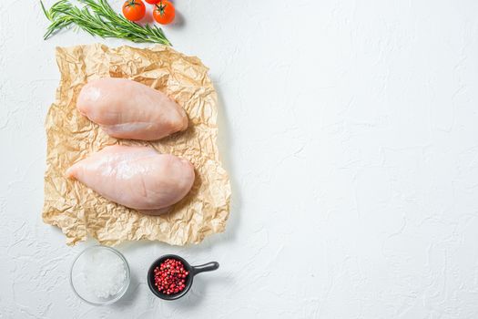 Raw meat, ready for grill or barbeque chicken breast filet, with herbs and spices on craft paper over white background, top view space for text