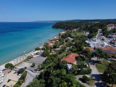 Aerial day view of Kallithea seafront at Kassandra peninsula with a beach bar by a clean tranquil blue sea.