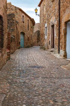 Old town street with lantern in Begur. Begur old town and castle with Estartit bay and Pyrenees mountains on the Spanish Costa Brava coast, Catalonia, Spain