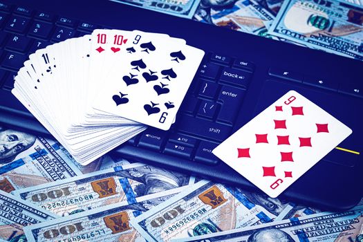 Hundred dollar bills, a deck of playing cards and a black keyboard. Concept of card games, casino or poker online. Online gambling.