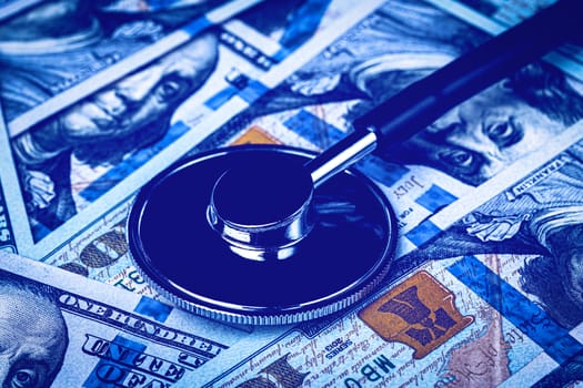 Stethoscope on the background of one hundred dollar bills. The concept of the expensive cost of healthcare or financing medicine.