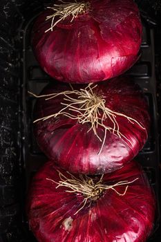 Farm red onions in tray on old oak wooden table. Close up top view. High quality.