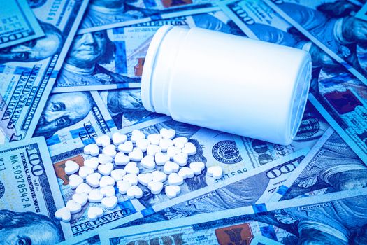 Heart-shaped pills on the background of hundred-dollar bills. The concept of the expensive cost of healthcare or financing medicine. White medicine bottle with copy space for text.