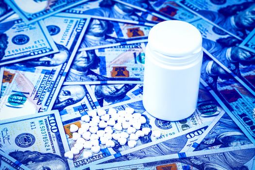 Heart-shaped pills on the background of hundred-dollar bills. The concept of the expensive cost of healthcare or financing medicine. White medicine bottle with copy space for text.